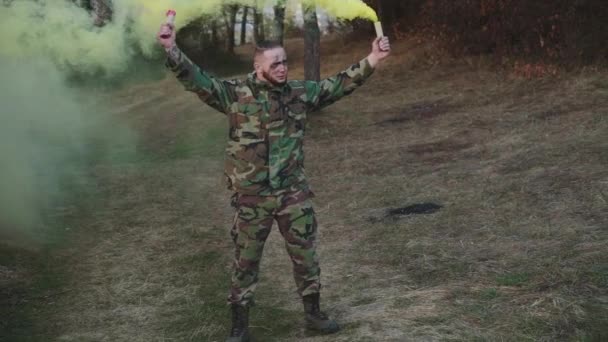 Soldat i kamouflage uniform och vandrar i naturen med färgad rök — Stockvideo