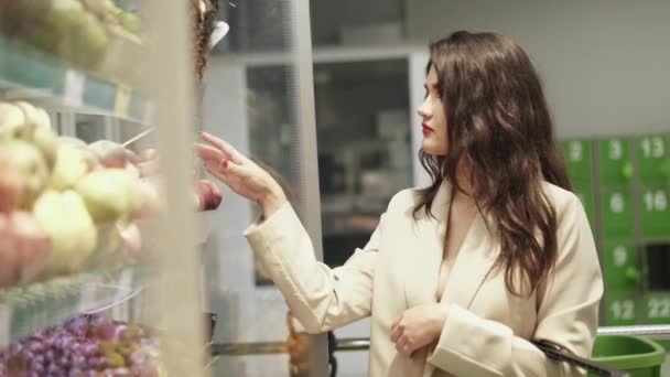 Jolie dame détermine la qualité d'une tomate rouge et la renifle dans un marché — Video