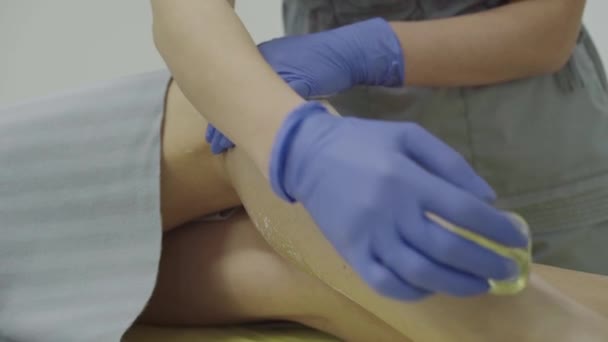 Vista da vicino di spalmare pasta di zucchero sulla gamba femminile dal maestro durante la depilazione — Video Stock