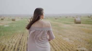 Sahada yürüyen zarif esmer ve rüzgar sırasında şapka takan