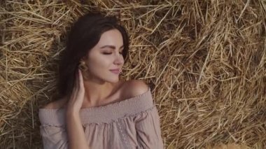 Mutlu esmer, gözleri kapalı samanlıkta yatıyor ve gülümseyerek boynunu okşuyor.