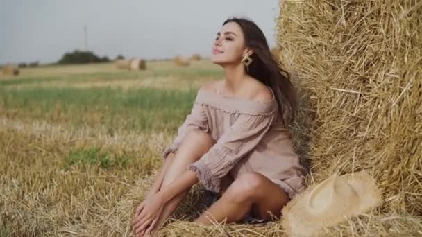 Mujer en vestido de verano descansando en un pajar en un campo y hablando con risa — Vídeos de Stock