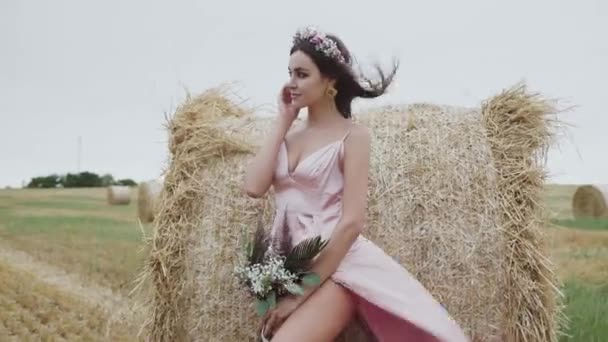 Dame passionnée pose doucement avec joie à la meule de foin dans un champ de vent spacieux — Video