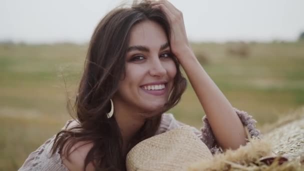 Menina em um campo, olhando ao redor e sorrindo para a câmera em tempo ventoso — Vídeo de Stock