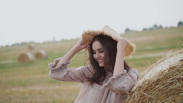 Felice giovane ragazza mettere cappello su soffiare capelli a haycock in campo ventoso — Video Stock