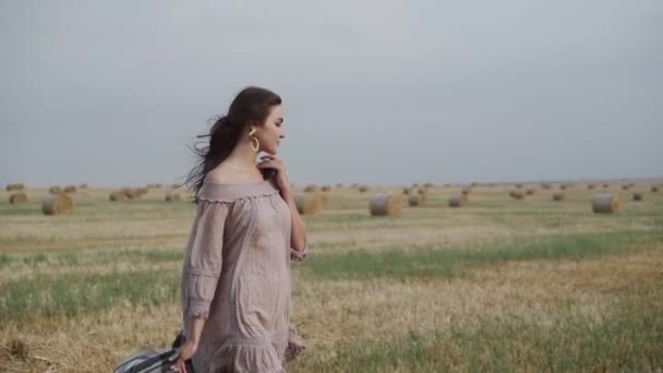 Bella ragazza tiene un plaid, ha gioia durante il vento nel campo e respira aria fresca — Video Stock