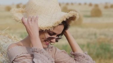 Zarif bayan saman tarlasında eğleniyor rüzgarla ve şapkayla gülümsüyor