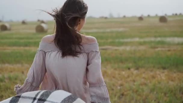 Menina caminha no campo com uma xadrez, deixa cair durante o vento, sorri e vira-se — Vídeo de Stock