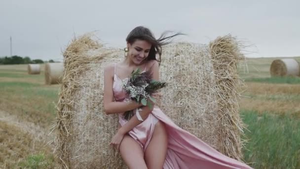 Senhora sedutora em soprar vestido de noite com buquê está em pose no palheiro — Vídeo de Stock