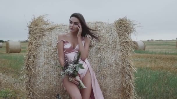 Дама в дуетній сукні з голими тонкими ногами пестить шию спокусливо на сінококу — стокове відео