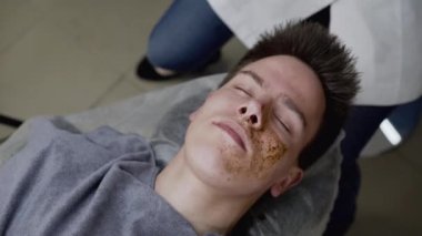 Güzellik uzmanlarının en iyi görüntüsü elleri, erkek yüzünü bir kahve fırçasının süngeriyle temizler.