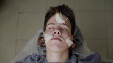 Sürünen salyangozlarla deri yenileme prosedürü uygulayan adamın görüntüsü.