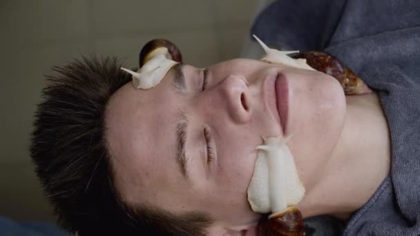 Близький портрет чоловіка, який отримує лікування обличчя для омолодження равликами — стокове відео