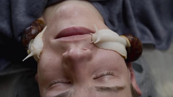 Чоловік отримує омолодження шкіри равликами на обличчі під час лікування — стокове відео
