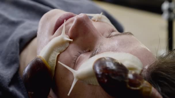 El hombre que recibe el procedimiento del rejuvenecimiento de la piel con los caracoles que se arrastran sobre la persona — Vídeo de stock