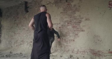 Kızgın sporcu, bir güreş sırasında terk edilmiş binadaki tozla adamı yere seriyor.