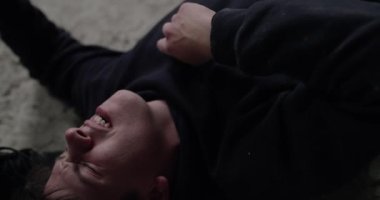 Dövülmüş adamın yakın görüntüsü, yerde yatıyor ve rakibinden son darbeyi alıyor.