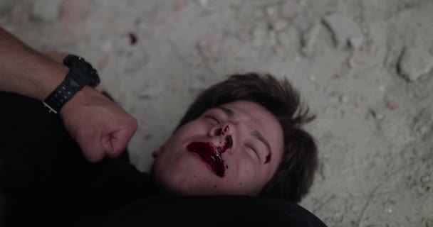 Widok zakrwawionego bijącego człowieka, leżącego na podłodze pod presją i mówiącego — Wideo stockowe