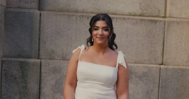 Güzel bir esmer gelin elinde buketle yürür ve kameraya bakar. 4K