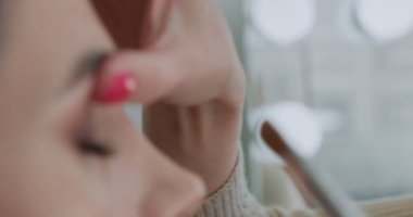 Profesyonel bir göz makyajı uygulamasına yakın çekim. Sanatçıların elinde göz farı olan bir fırça. Yavaş çekim