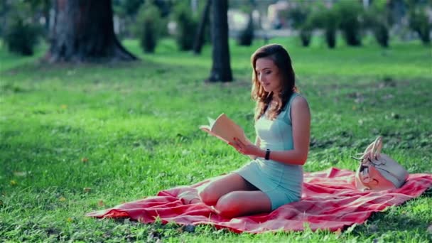 Niña soñadora en el parque leyendo un libro — Vídeo de stock