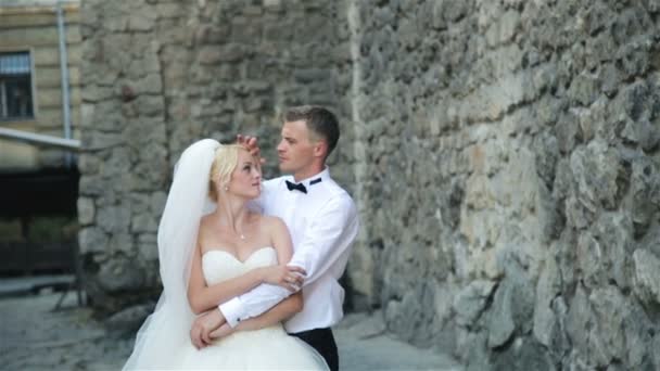 Schönes Hochzeitspaar an einer Mauer aus Stein — Stockvideo