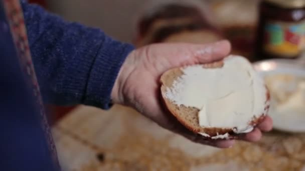 Mano vieja extendiendo mantequilla en un pedazo de pan — Vídeos de Stock