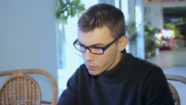 Guy with glasses in a cafe with tablet — Stock Video