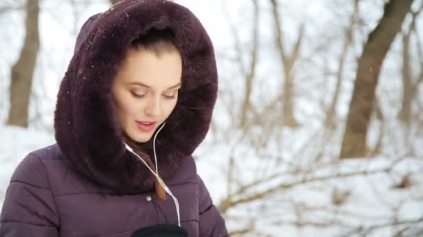 Na zewnątrz na zimowy dzień. dziewczyna słuchać muzyki. — Wideo stockowe