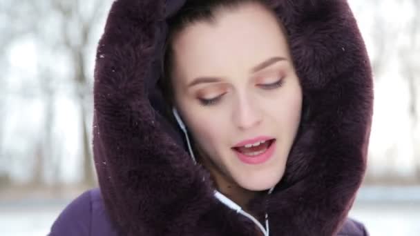 La ragazza ascolta musica e la neve cade — Video Stock