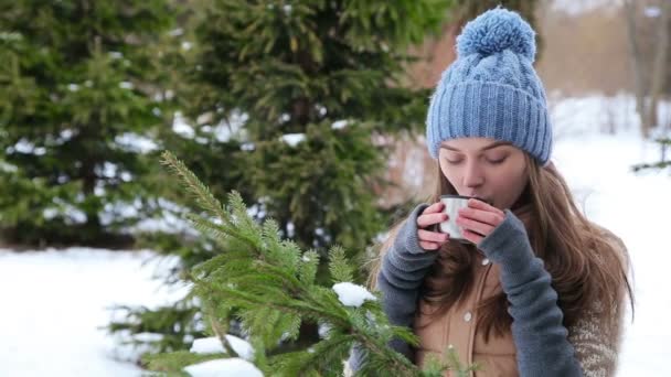 Красива дівчина п'є гарячий чай взимку на відкритому повітрі — стокове відео