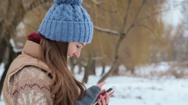 Kış parkta bir smartphone cep telefonu ile konuşurken kız