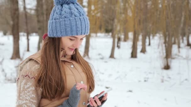 Ragazza che parla su uno smartphone nel parco invernale — Video Stock