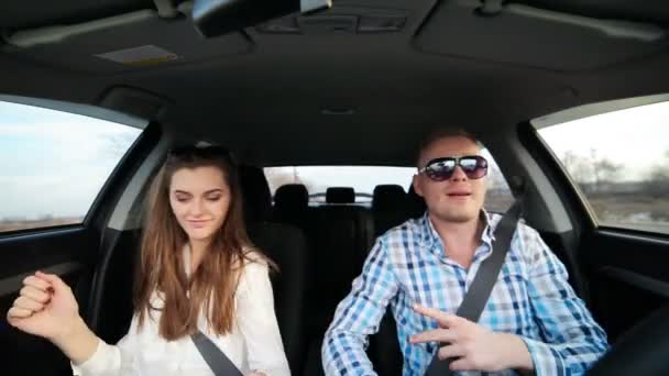 Hombre guapo conduciendo coche haciendo bailar a chica divertida — Vídeo de stock
