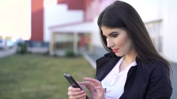 Zufriedene Geschäftsfrau schaut aufs Smartphone — Stockvideo