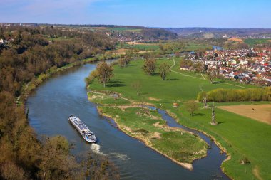 Yeşil bir arazide bir botla dolambaçlı bir nehrin hava görüntüsü. Bad Wimpfen yakınlarındaki Offenau civarında.