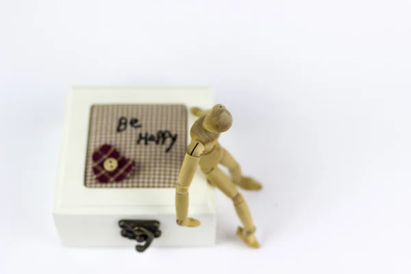 Wooden puppet sitting on a jewellery box — Stock Photo, Image