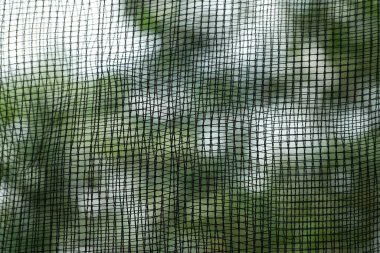 Bulanık yeşil doğa arka planına sahip siyah tarımsal ağ dokusunu kapat