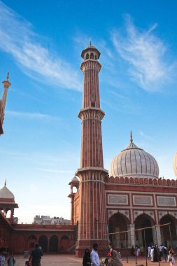 Delhi, Hindistan, 28 Kasım 2025. Uzun Minare ve Kubbe Jama Mescidi Açık Mavi Gökyüzü Altında Avluda Yükseliyor
