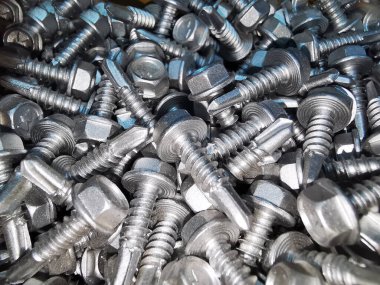 Çelikten yapılmış pek çok metal vida var, metal için kendi kendine vurabilen vida, demir için kendi kendine vurabilen vida, krom kaplama kendi kendine vurabilen vida, arka plan olarak dağınık vidalar.