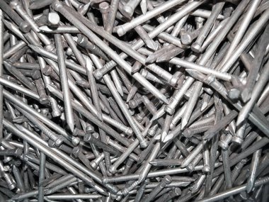 Arka planda çelikten metal çiviler, demir çiviler, krom çiviler var..