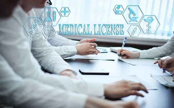 Modern bir klinikte bir grup doktor planlanıyor. Modern tıp ve tıbbi biyoloji kavramı. Ekranda yazılı tıbbi simgeler: MEDICAL Lisans
