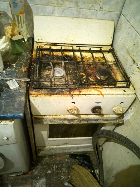 Dirty and rusty top of a kitchen gas stove with pieces of debris, food and burning, dirt stains, used for cooking.