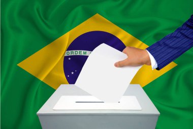 Ülkedeki seçimler - oy sandığında oy kullanma. Bir adam oyunu sandığa koyuyor. Arka planda Brezilya bayrağı.