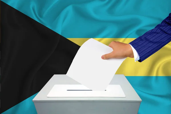 国内の選挙 投票箱で投票する 男の手が投票箱に投票する バハマを背景に旗 — ストック写真