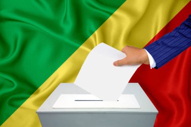 Ülkedeki seçimler - oy sandığında oy kullanma. Bir adam oyunu sandığa koyuyor. Arkaplanda Bayrak Kongosu.