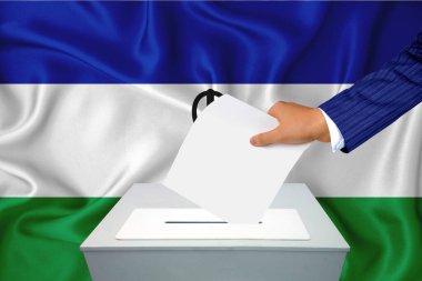 Ülkedeki seçimler - oy sandığında oy kullanma. Bir adam oyunu sandığa koyuyor. Arka planda bayrak lesotho.