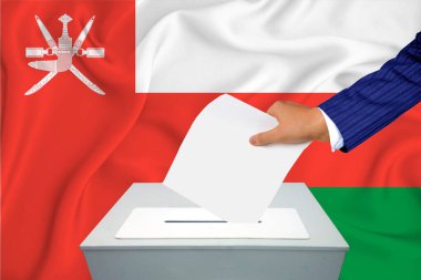 Ülkedeki seçimler - oy sandığında oy kullanma. Bir adam oyunu sandığa koyuyor. Arka planda Umman Bayrağı.