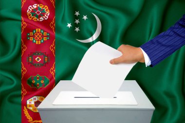 Ülkedeki seçimler - oy sandığında oy kullanma. Bir adam oyunu sandığa koyuyor. Arkaplanda Türkmenistan bayrağı.