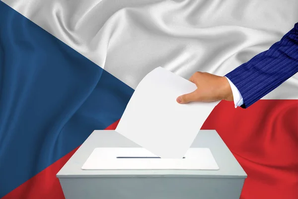 Elections in the country - voting at the ballot box. A man's hand puts his vote into the ballot box. Flag Czech on background.